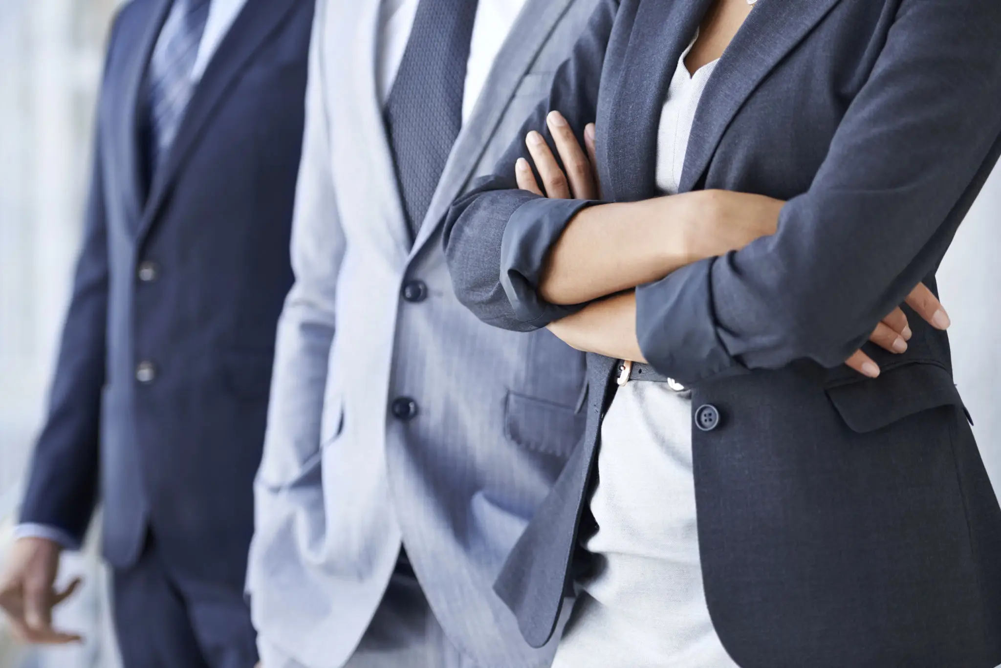 Close-up of business professionals in suits with crossed arms.