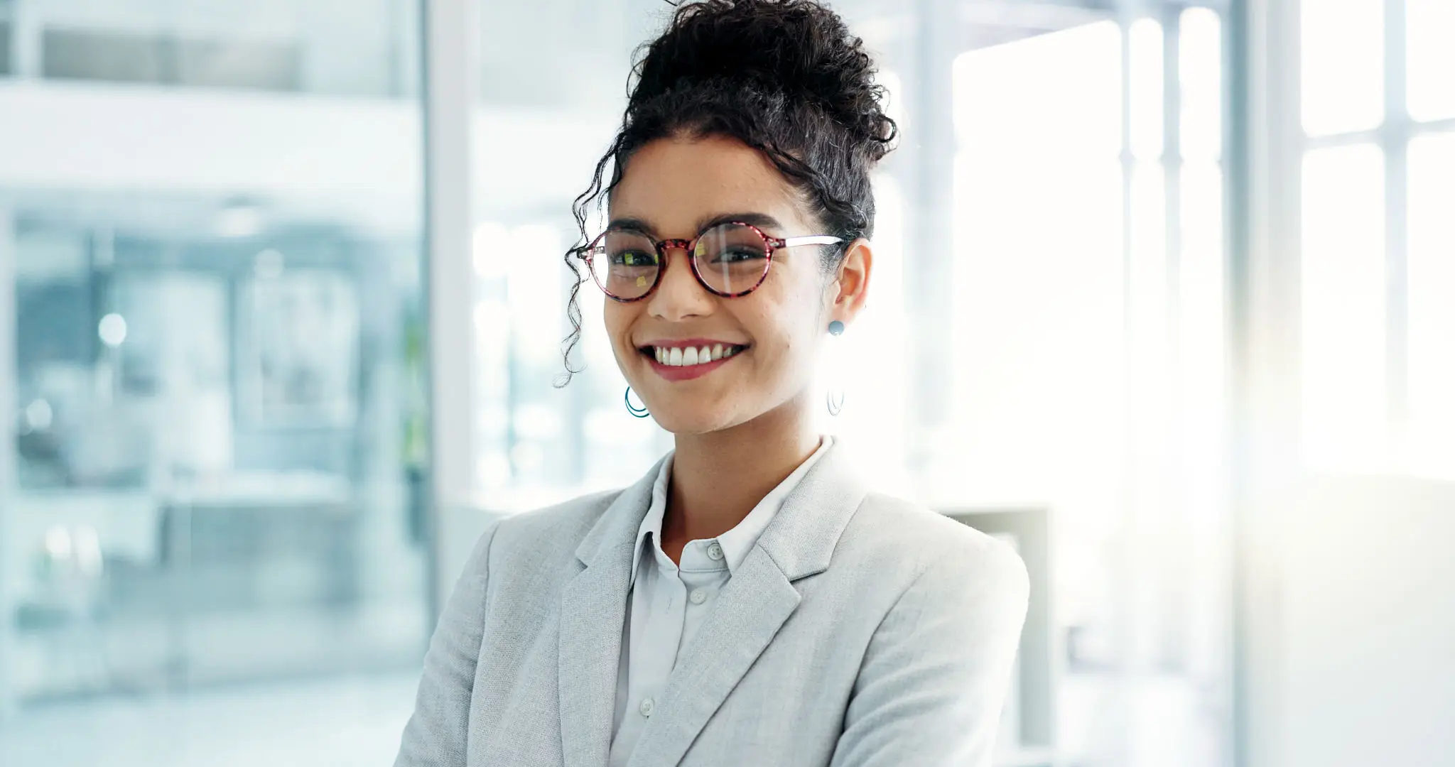 Confident young woman with glasses smiling in a professional setting.