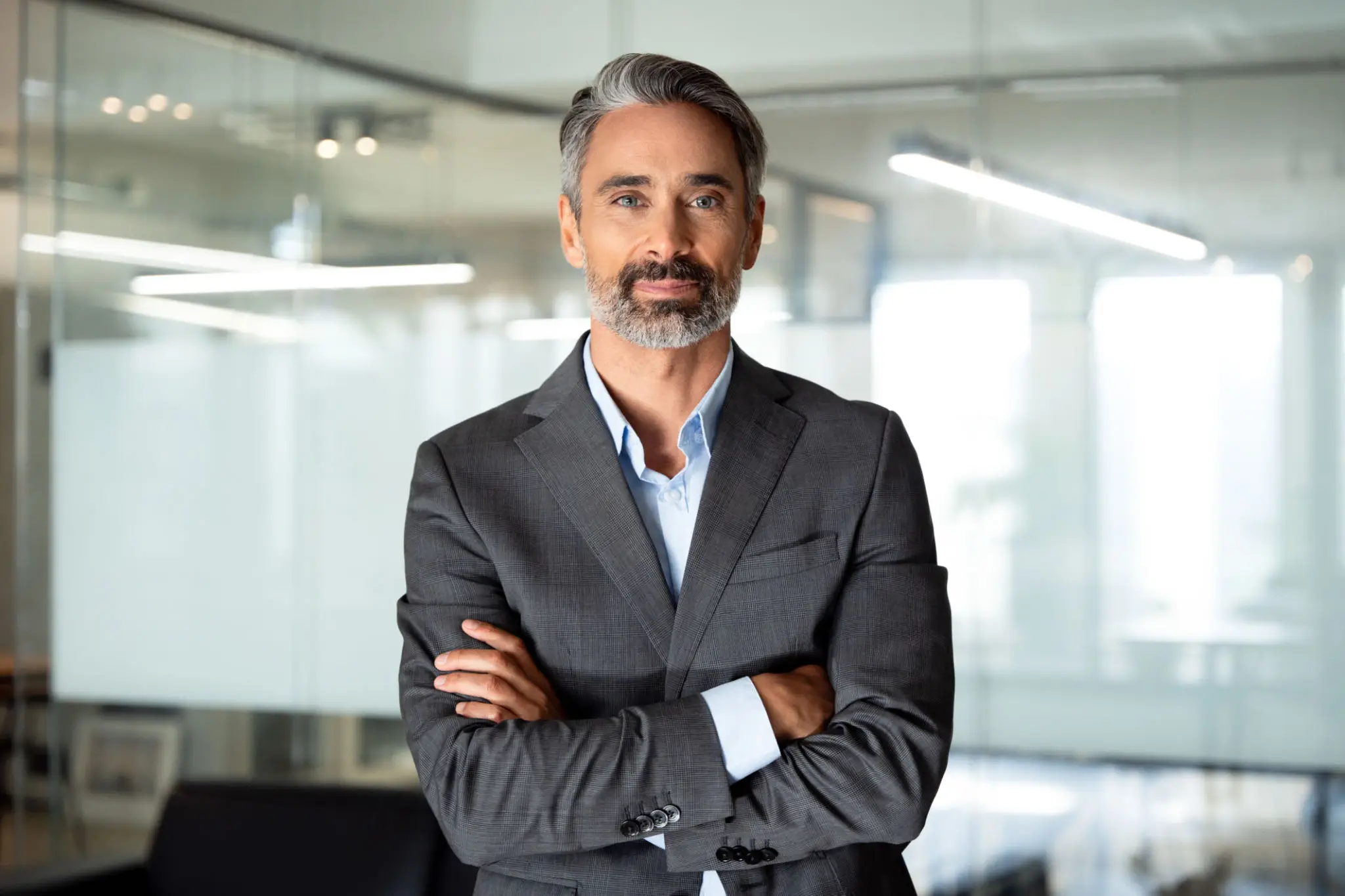 Confident middle-aged businessman with folded arms in a modern office.