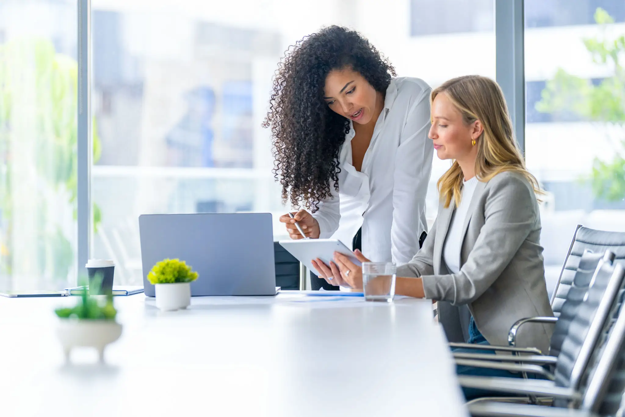 Two professional women collaborating with a tablet in an office.