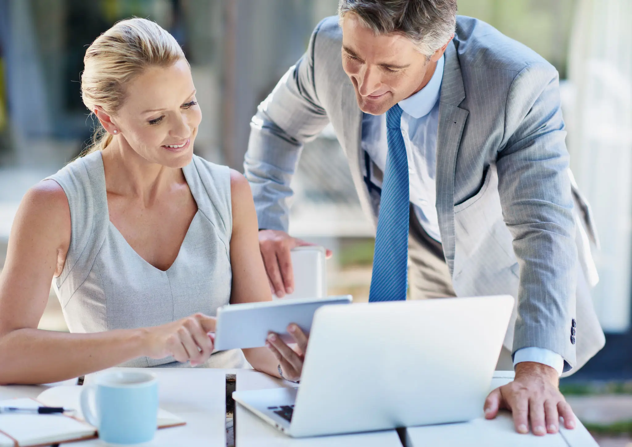 Two business professionals collaborating over a laptop and documents.